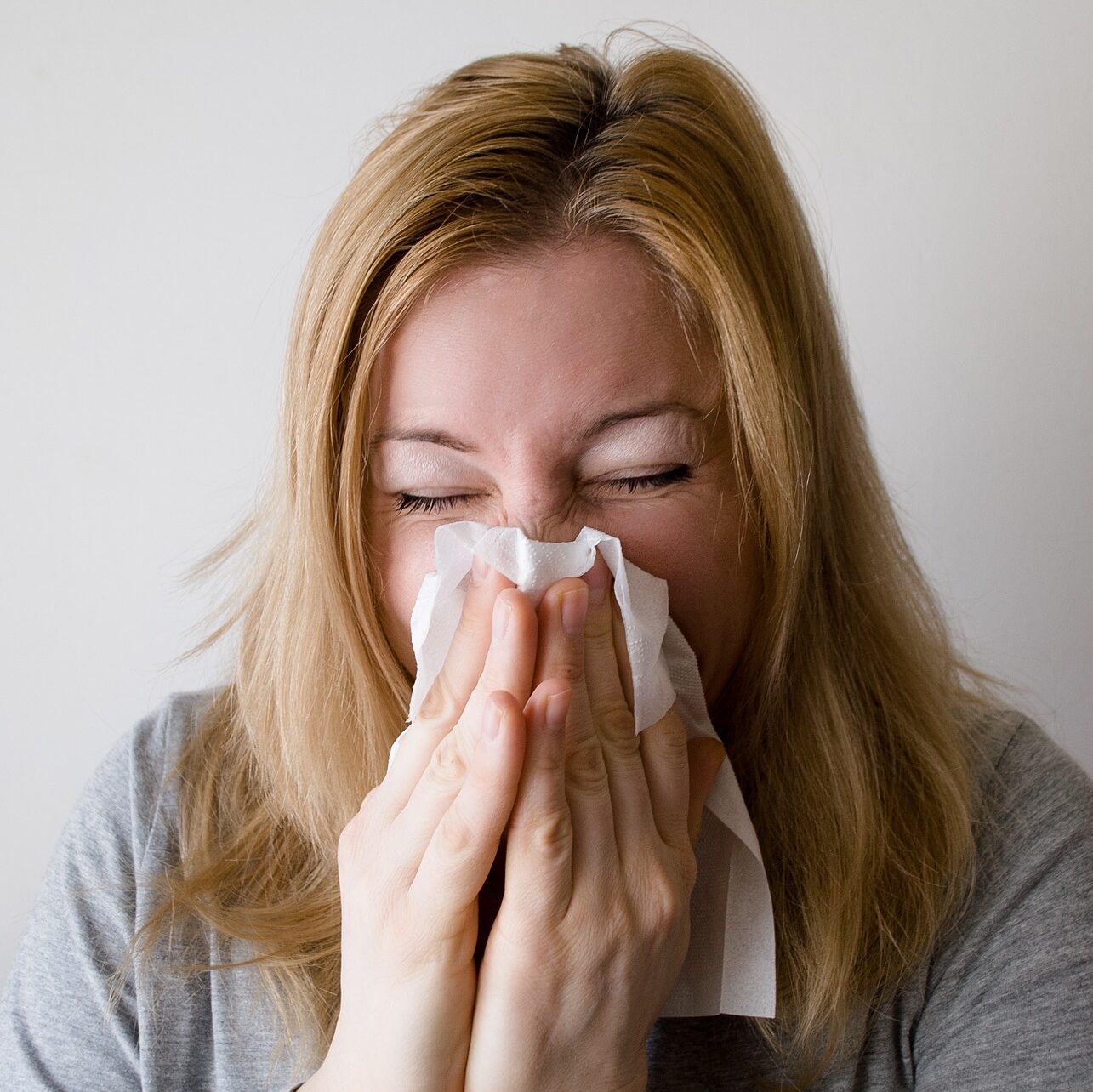 A woman holding a tissue to her nose